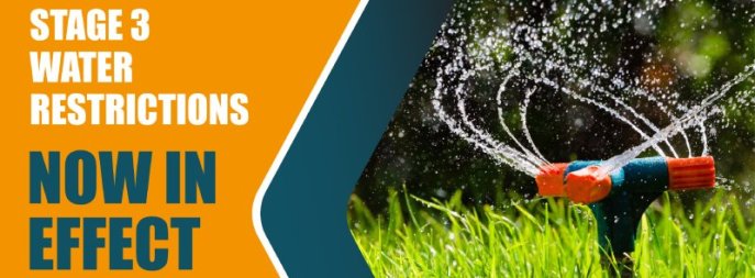 water restrictions text next to sprinklers spraying water on lawn 